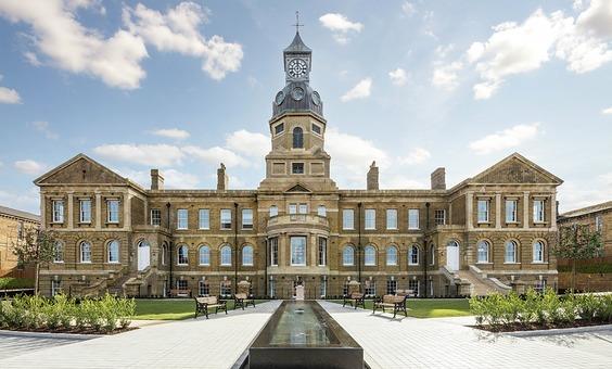 Gun Hill Park in Aldershot, which is the restored Cambridge Military Hospital. The image shows the grandeur of the building with staircases either side. A water feature leads the eye to the ornate, tall clock tower in the centre.